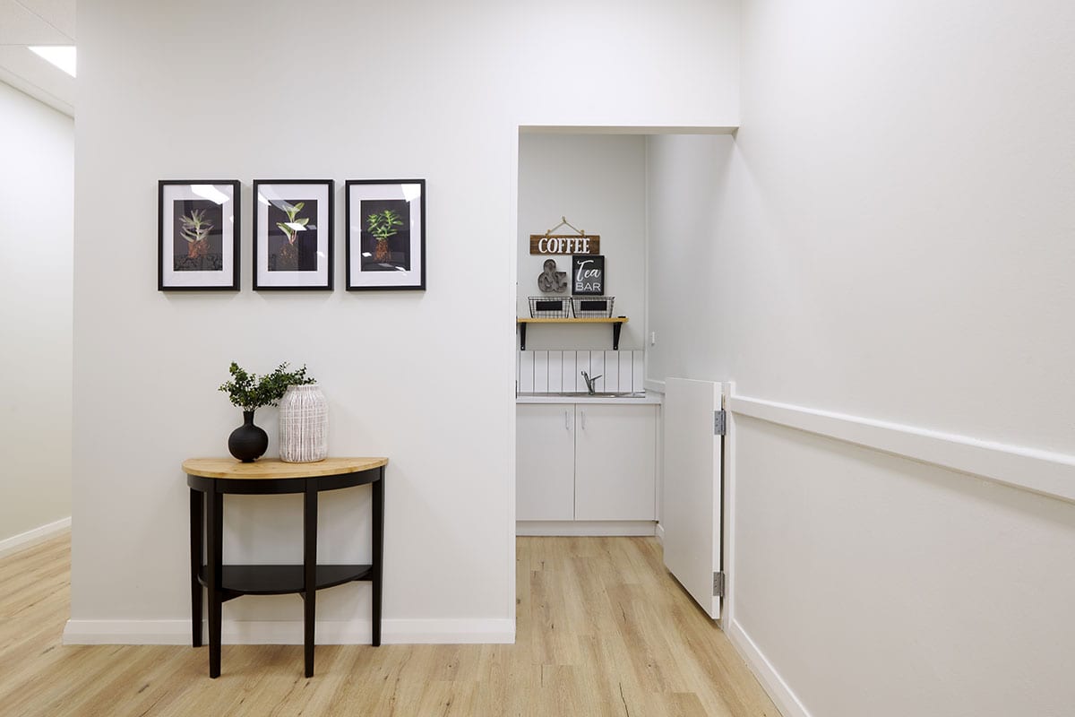 White interior with black photo frames hanged on wall of parents tea and coffee room entrance