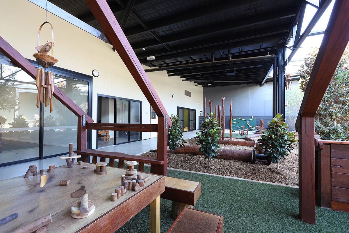 Corner view of outdoor garden area with wooden play toys