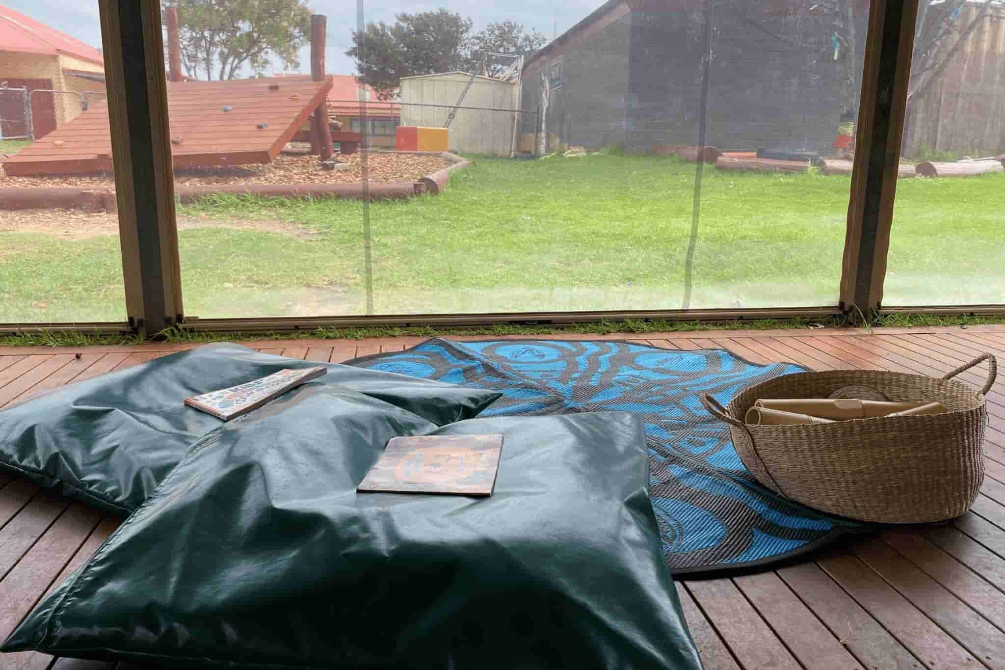 floor seating area with cushions looking outside window to playground