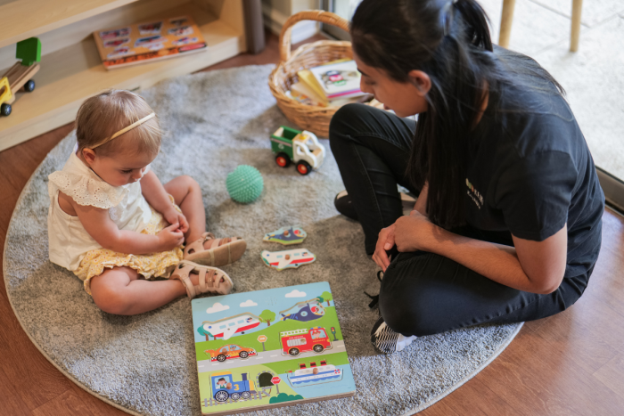 baby and educator looking at puzzle on mat