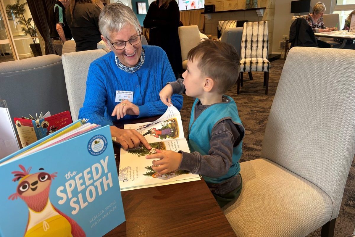child and aged care resident reading at intergenerational playgroup