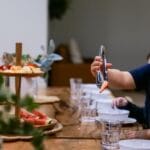 boy using tongs to pick up strawberries at dining table